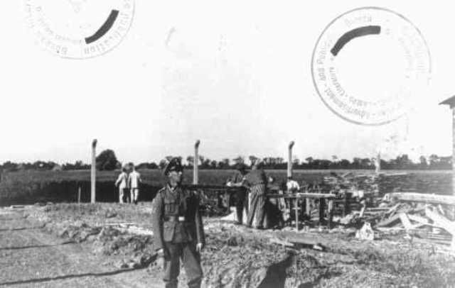 An SS guard watches prisoner laborers at construction work. Neuengamme concentration camp